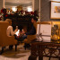 Giftvoucher in foreground on accent table. Unfocused couple in background enjoying champagne in front of a fire place with lit fire and festive decoration